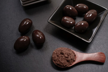 Chocolate round with cocoa powder wooden spoon and plate on top of Black rock stone plate