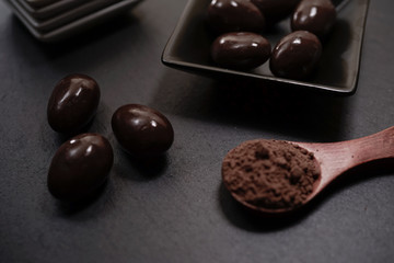 Chocolate round with cocoa powder wooden spoon and plate on top of Black rock stone plate