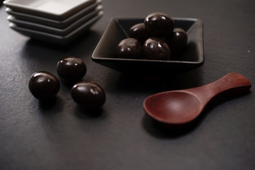 Chocolate round with cocoa powder wooden spoon and plate on top of Black rock stone plate