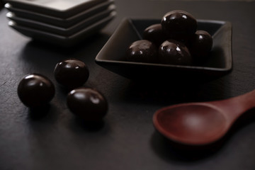 Chocolate round with cocoa powder wooden spoon and plate on top of Black rock stone plate