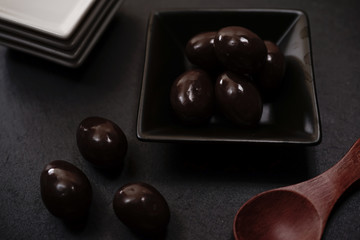 Chocolate round with cocoa powder wooden spoon and plate on top of Black rock stone plate