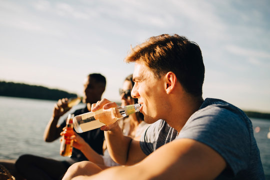 Man sitter med v&permil;nner p&Acirc; brygga och dricker ur flaska