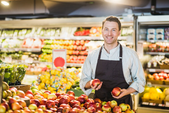Portr&permil;tt av leende &permil;gare vid fruktdisken i matvarubutik