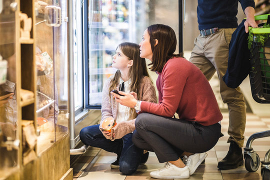 Mamma och dotter tittar p&Acirc; varor i kyldisk i mataff&permil;r