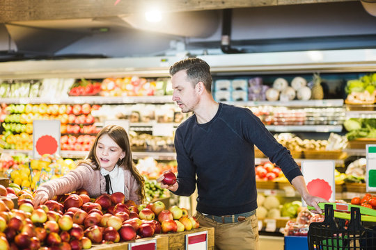 Pappa och dotter v&permil;ljer &permil;pplen i mataff&permil;r