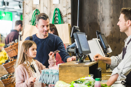 Pappa hj&permil;lper dotter att betala i kassan i matvarubutik