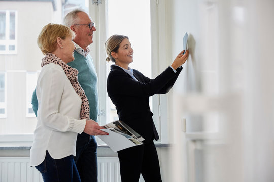 Smiling female estate agent showing color samples to retired couple at new home