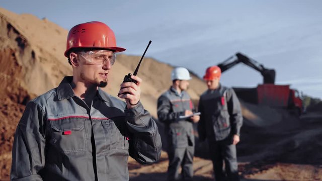 Male industrial engineer talking using walkie talkie at construction site medium shot