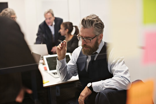 Fundersam man planerar med kollegor under m&circ;te i konferensrum
