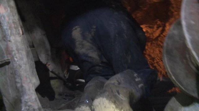 A close up of the backs of miners walking down a tunnel in a mine
