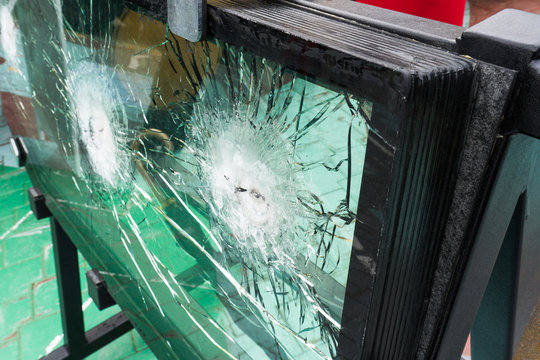The bulletproof glass after the test, cracks and dents on the window from the bullet at the exhibition of weapons
