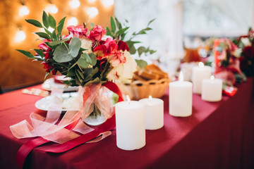 boho wedding decor. festive table with burgundy tablecloth. decoration of the hall garland with light bulbs.