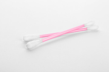 Pink plastic cotton swabs on white background