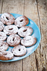 Fresh baked chocolate chip cookies with sugar powder on blue plate on rustic wooden table.