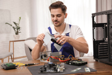 Male technician repairing power supply unit at table indoors