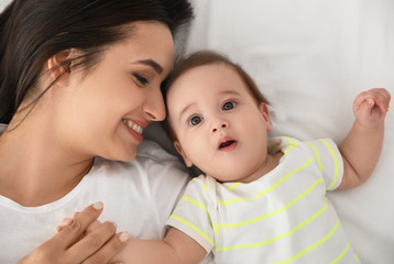 Portrait of mother with her cute baby lying on bed, top view
