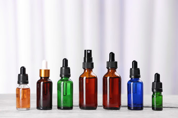 Bottles of essential oils on table against light background. Cosmetic products
