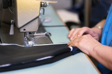 Seamstress sews clothes on a sewing machine. Textile factory .