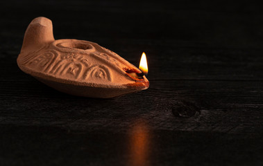A Lit Handmade Oil Lamp from the Middle East on a Dark Table