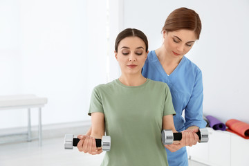 Fototapeta premium Professional physiotherapist working with female patient in rehabilitation center