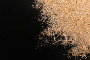 Golden paint on black background. Space for text