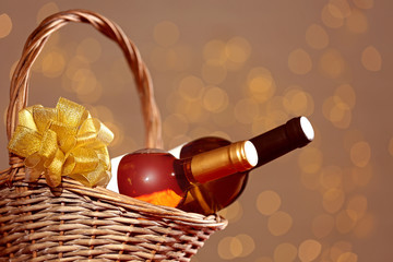 Bottles of wine in wicker basket with bow against blurred lights