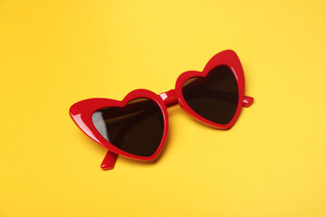 Stylish heart shaped glasses on color background