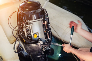 mechanic repairing inflatable motorboat engine at boat garage. Ship engine seasonal service and...