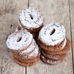 Fresh baked chocolate chip cookies with sugar powder stacks on wooden table.
