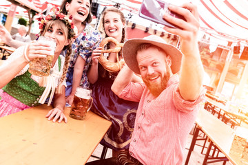 Gruppe von Freunden machen Selfies auf dem Oktoberfest im Bierzelt mit Bier beim Feiern 