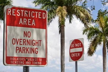 Restricted Area No overnight Parking Sign. Red and white warning sign and DoNot Enter sign, with palm trees and partly cloudy sky in backgroun - obrazy, fototapety, plakaty