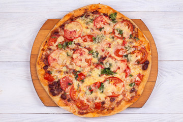 Top view of domestic pizza on white wooden background