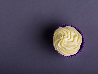 Cupcake in purple wrap on dark blue background. Minimalist. Top view with copy space.