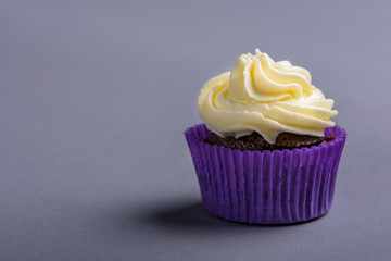Cupcake in purple wrap on blue background. Minimalist. Copy space.