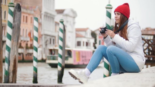 Young woman sitting on concrete blocks and takes pictures all around