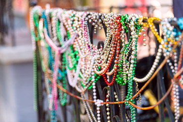 New Orleans, USA closeup of mardi gras beads hanging on fence by colorful building house and nobody...