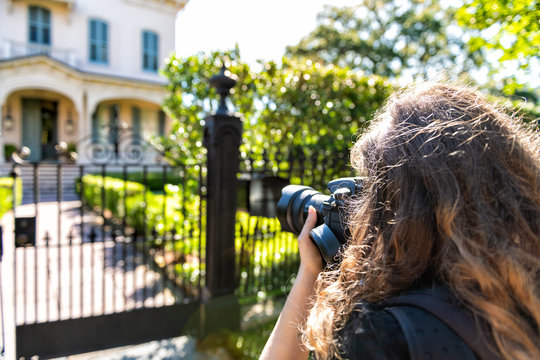 New Orleans, USA Old historic Garden district in Louisiana with green spring summer day and woman photographer taking picture of house with camera