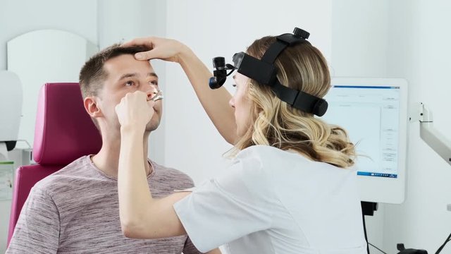Doctor ENT checking nose with otoscope to men patient. Consultation with a doctor.