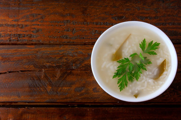 congee in ceramic bowl on rustic wooden table, traditional rice porridge typical of Asian cuisine