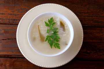congee in ceramic bowl on rustic wooden table, traditional rice porridge typical of Asian cuisine