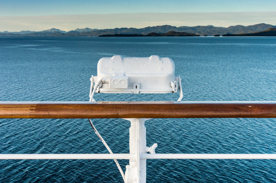 White metal exterior light fixture on railing of cruise ship, Alaska Inside Passage route.