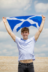 Caucasian male on a beach holding a Scottish flag