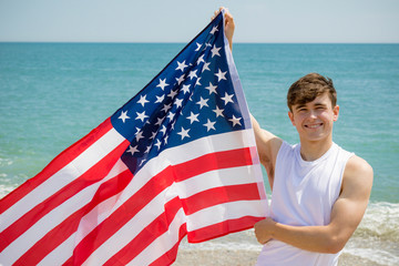 Caucasian male on a beach holding an American flag