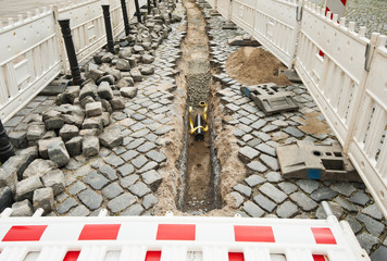 Einbau von Leerrohr in einer Strasse aus grossen alten Pflastersteinen