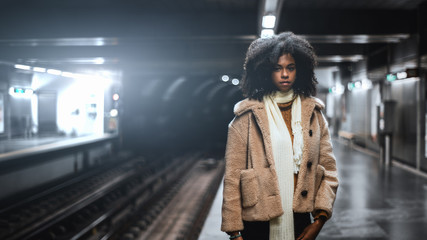 A dazzling African-American girl with curly lush Afro hair in a demo-season coat and scarf is...
