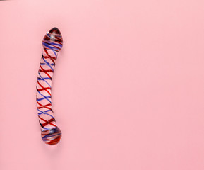 Beautiful evenly lit glass dildo on a plain pink background with copy space.