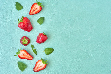 Ripe strawberries with mint leaves on a bright blue background. Fresh fruits composition. Fruit background. Top view