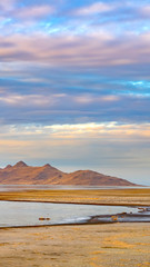 Vertical Panorama of a calm lake with vast sandy shore under cloud filled sky