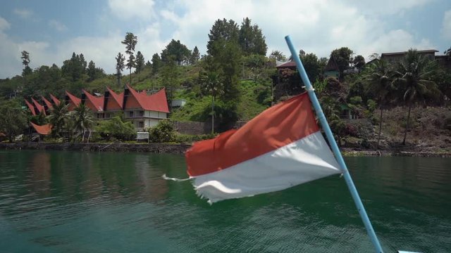Slow motion of the Indonesia flag blowing in the wind on a ferry boat crossing Lake Toba in North Sumatra.