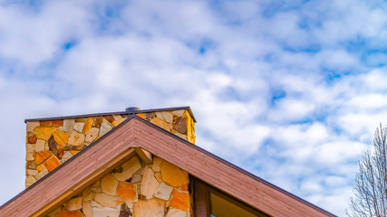 Panorama frame Close up of the roof of a house against trees and sky with cottony clouds